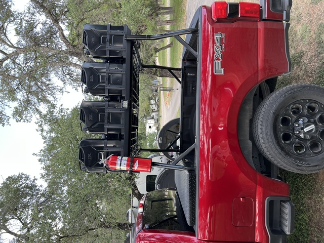 Side of the red F250 with four jerry cans mounted above the bed