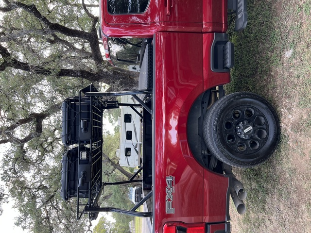 Side of the red F250 with two waterproof travel cases on the ladder rack